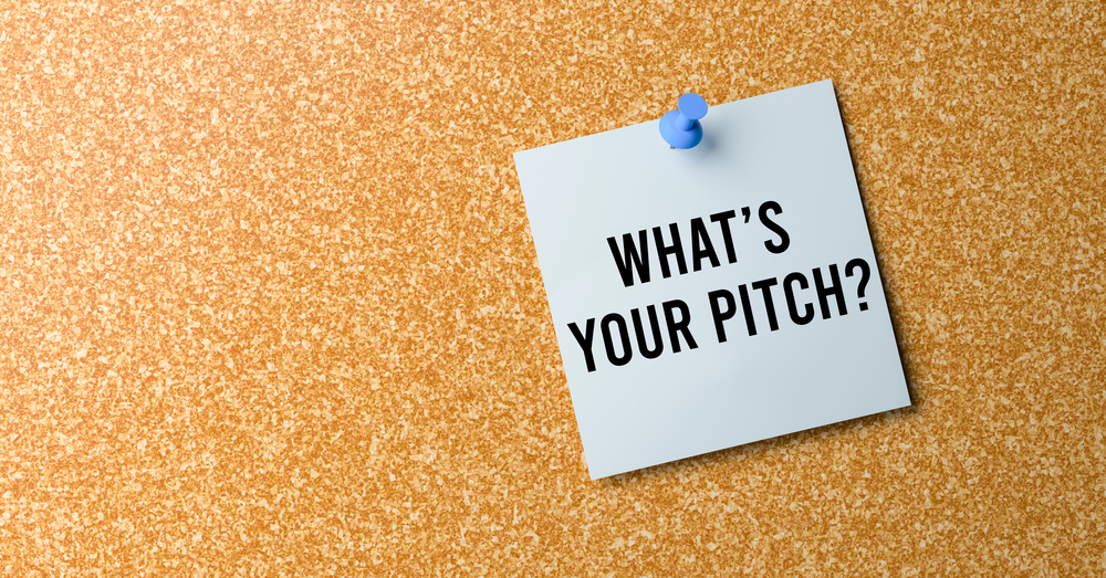 A corkboard with a white note pinned to it. The note reads, "WHAT'S YOUR PITCH?" in bold black letters.