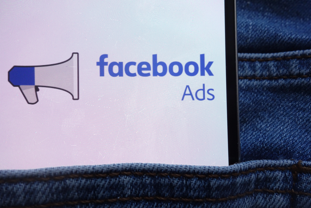 A smartphone partially tucked into the back pocket of blue jeans displays the logo and text "Facebook Ads" alongside a megaphone icon.