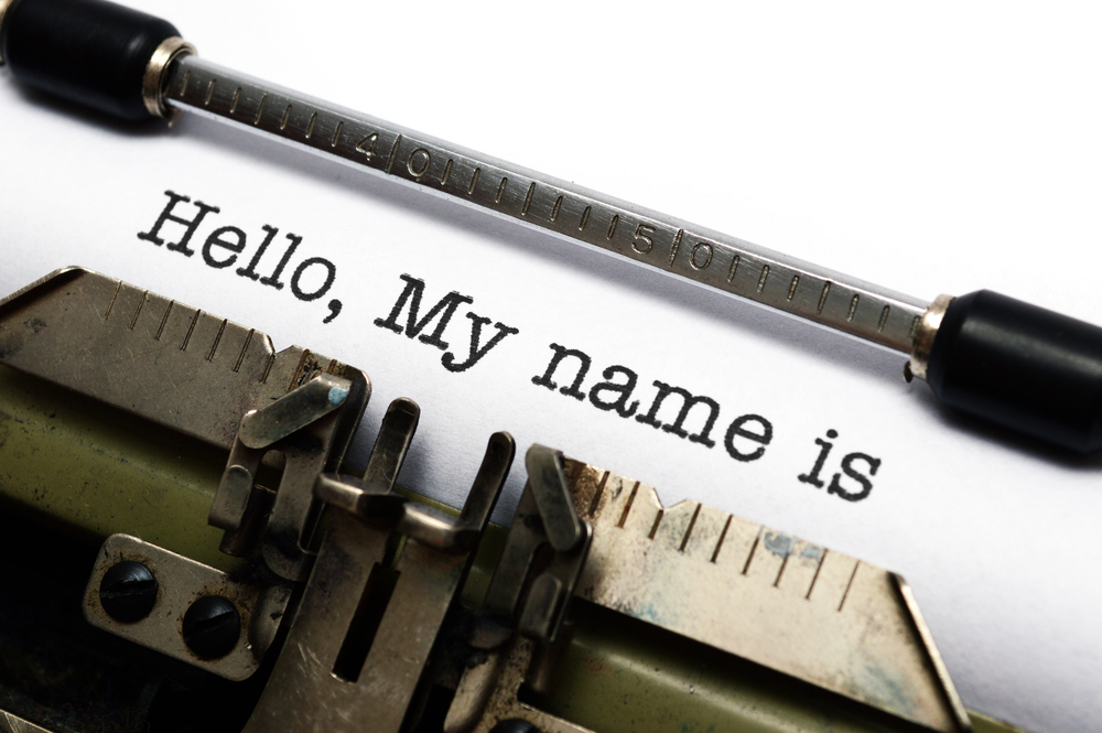 Close-up of a vintage typewriter typing "Hello, My name is" on a white sheet of paper.