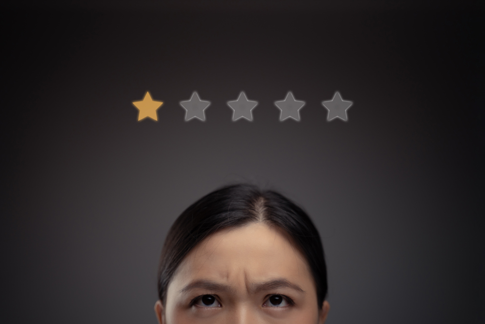 A person looks up with a concerned expression at a row of five stars, with only the first star highlighted in yellow. The background is dark, emphasizing the person's expression and the star rating.